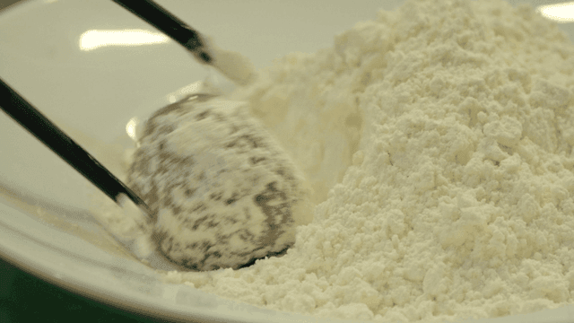 Meatball being coated in flour
