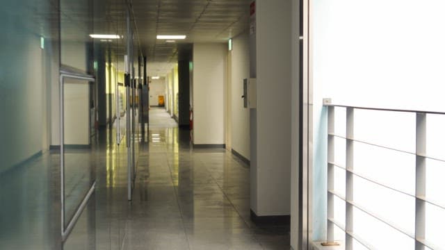 Woman walking down a hallway holding a red folder