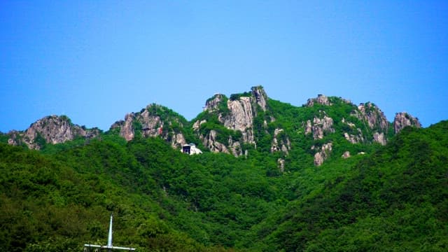 맑고 푸른 하늘 아래 울창한 녹색 바위산