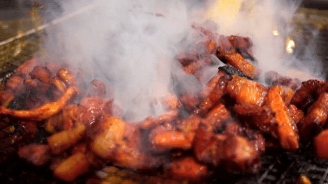 그릴 위에서 연기와 함께 구워지는 양념된 삼겹살