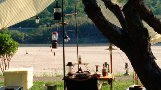 Resting under a tent on the riverside decorated with camping equipments