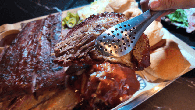 Texas barbecue brisket picked up with tongs and transferred to plate