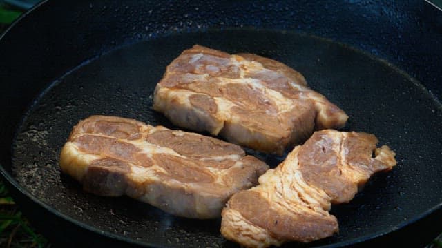 Grilling of juicy marinated pork on a hot frying pan