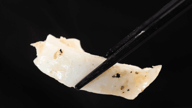 Chopsticks holding a piece of grilled squid