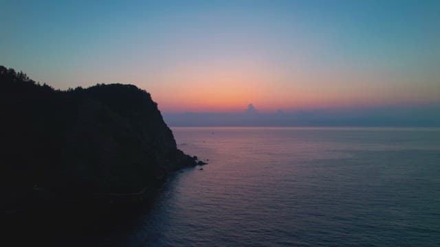 Sunset over a calm ocean and cliff