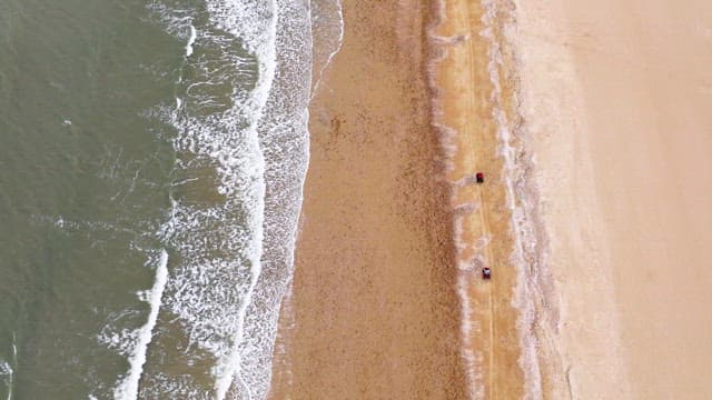 흐린 하늘 아래 넓은 해변에서 ATV를 타는 사람들