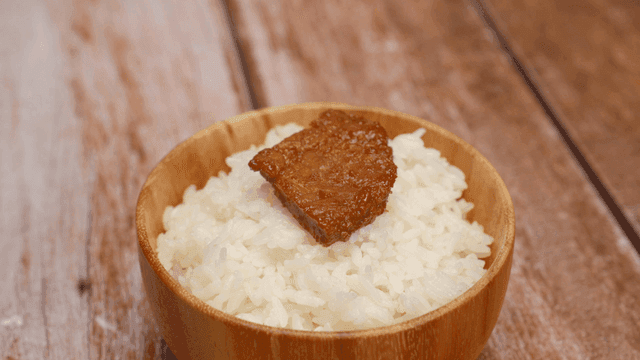 밥 위에 양념 고기 한 조각이 있는 그릇