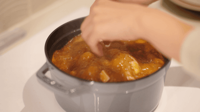 Hand putting tofu into soybean paste stew boiling in pot