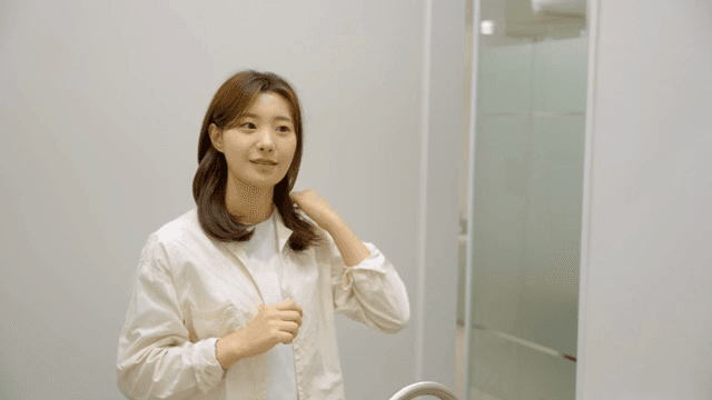 거울 앞에서 머리를 정리하는 여성