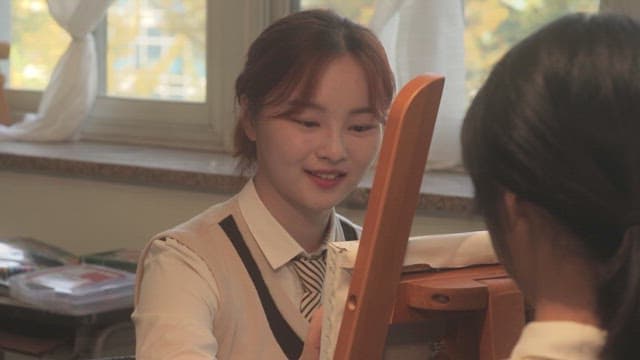 Two students painting a portrait in a classroom