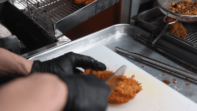 Pork cutlet being sliced ​​on kitchen cutting board