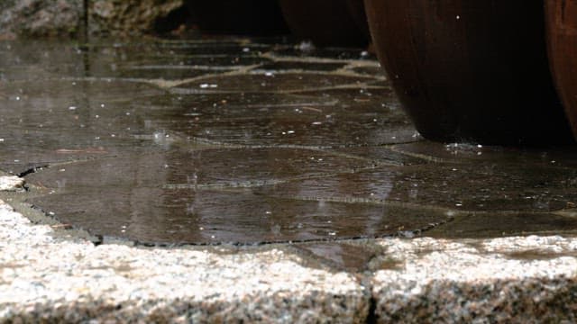 Rain falling on a stone tile pavement outdoors