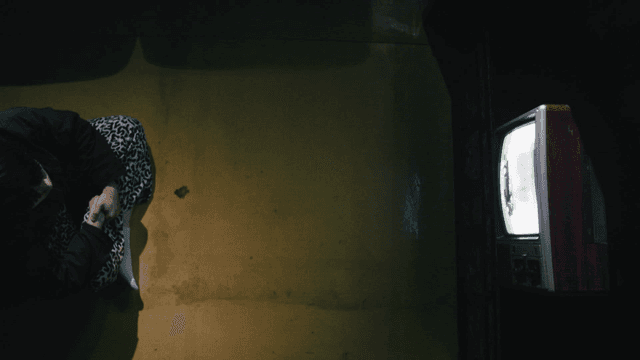 Old student sitting in dark room watching TV