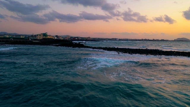 황혼에 파도와 도시 경관이 어우러진 해안 전망