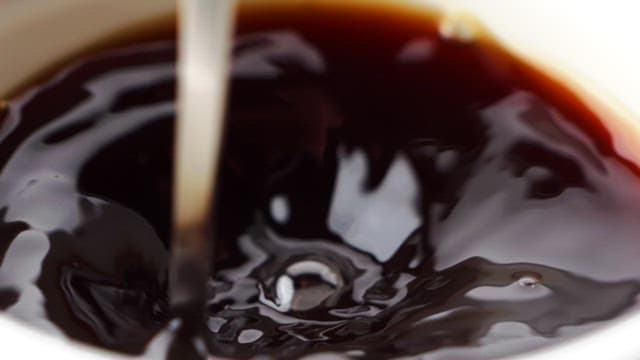 Stirring coffee in a white cup with a spoon