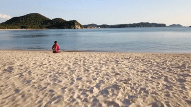 바닷가 모래사장에 앉아 있는 사람