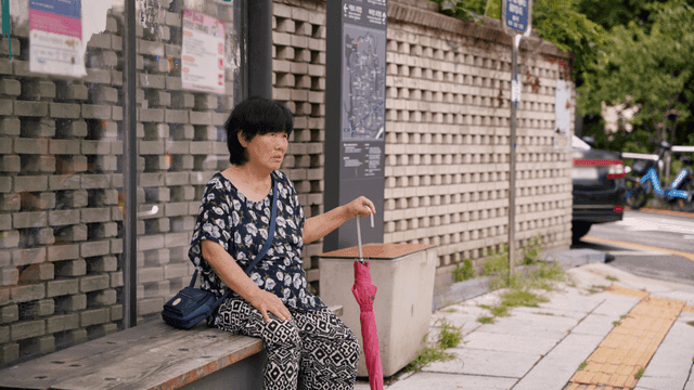 버스정류장에 앉아 대화하는 노인 여성