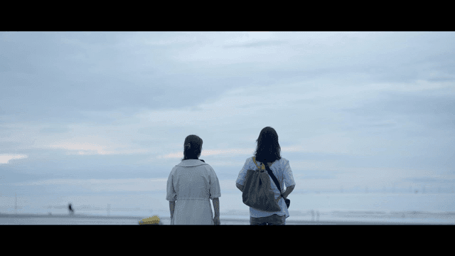 Backs of two women standing on quiet beach