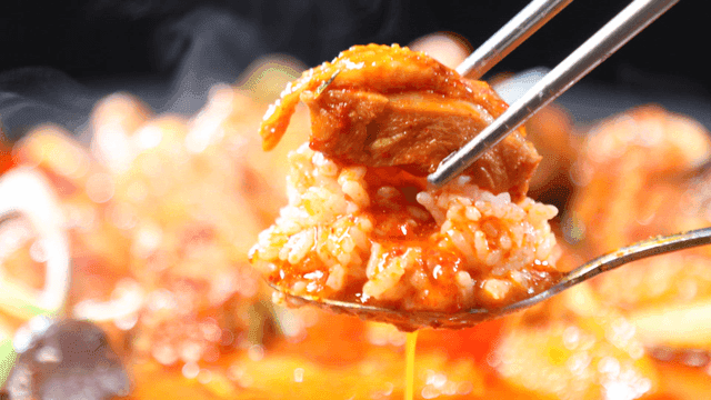 Rice and chicken dipped in spicy braised chicken broth on spoon