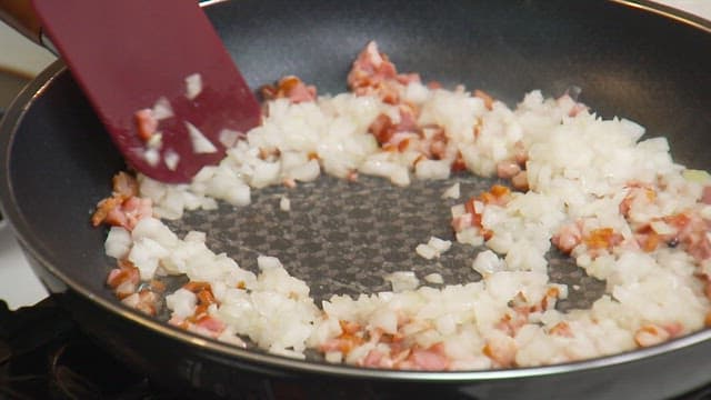 Stir-frying minced onions and bacon in a frying pan