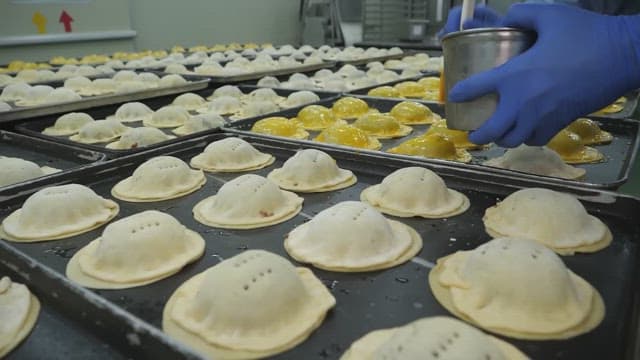 Bread dough being brushed with egg wash in a bakery kitchen