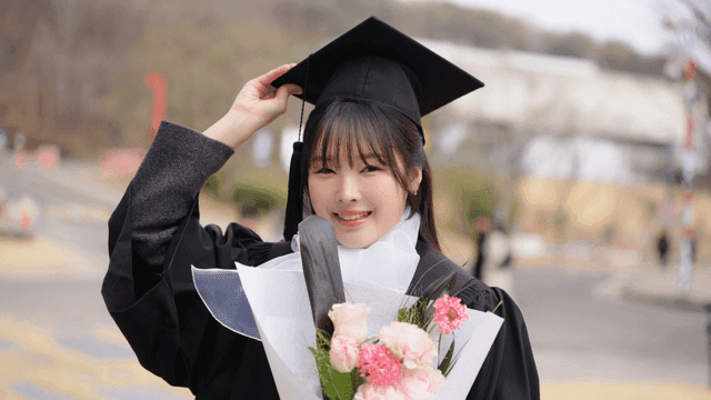 Graduate holding flowers with a smile