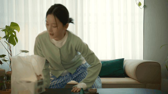 Woman sitting on sofa holding plastic bag of chicken
