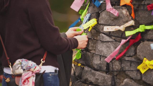돌담에 색색의 리본을 묶는 사람
