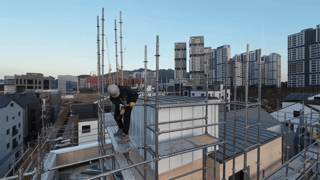 도시 풍경 속 비계 위의 작업자