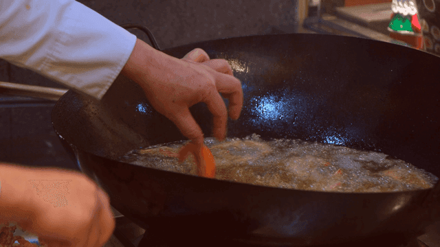 Chef frying shrimp in large wok