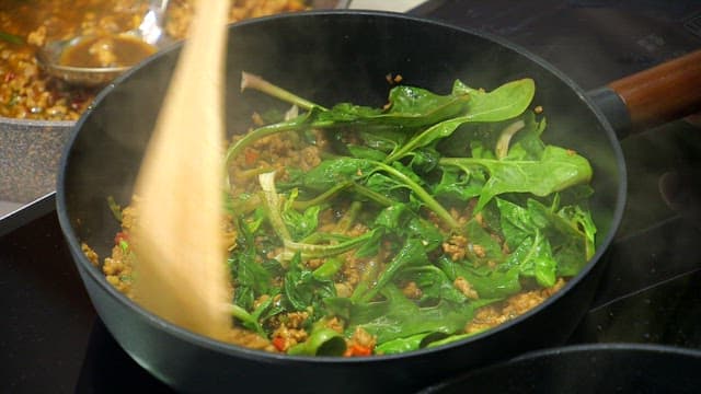 Stir-frying spinach and minced meat in a pan