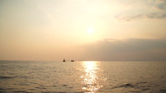 Sunset over the calm ocean with distant ships