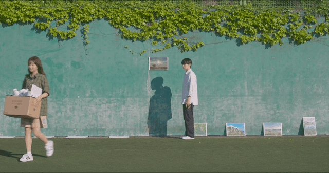 Woman leaving with box and man watching