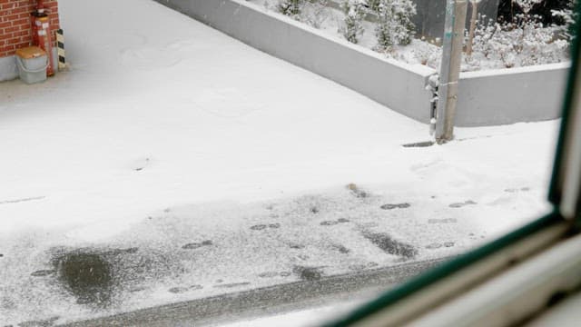 Person with umbrella walking on snow-covered street