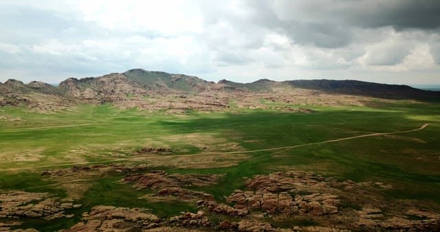 Expansive green plains with rocky mountains