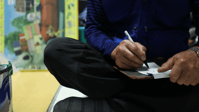 실내에서 청구서에 글을 쓰는 노인