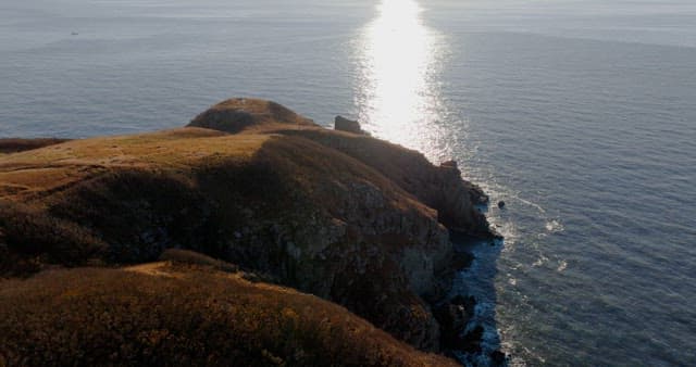 Serene Coastal Landsacape with Sun Reflecting on Water