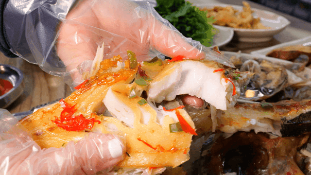 Glove-wearing hands tearing steamed dried rockfish