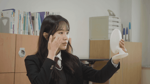 거울을 보며 머리를 정리하는 학생