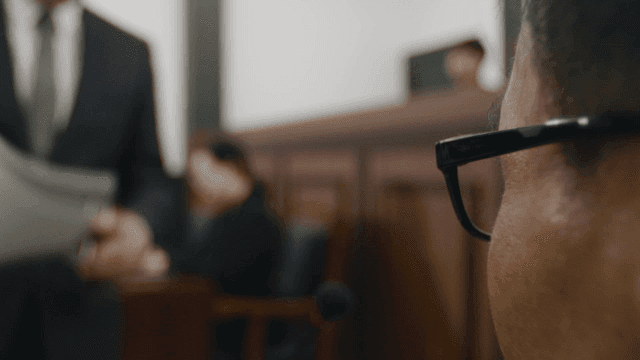 Profile of person in courtroom with judge and lawyers