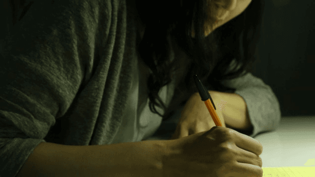펜으로 메모장에 글을 쓰는 여성