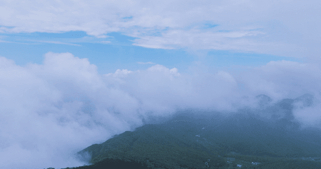 Clouds drifting over lush green mountains