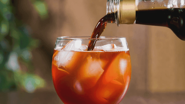 Cold brew coffee being poured into glass filled with ice