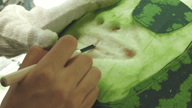 Carving patterns on watermelon rind with chisel