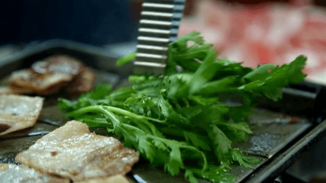 뜨거운 그릴 위에 쑥갓과 함께 삼겹살 굽기