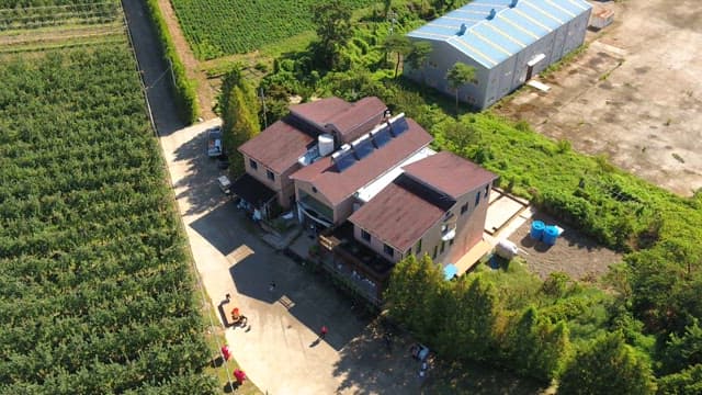 Aerial view of a large house surrounded by farmland on a sunny day