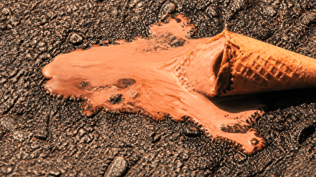 Melted chocolate ice cream cone on asphalt