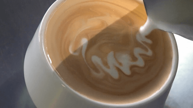 Milk being poured into a cup of coffee