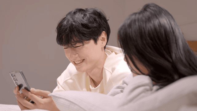 스마트폰을 보며 침대에서 쉬는 커플