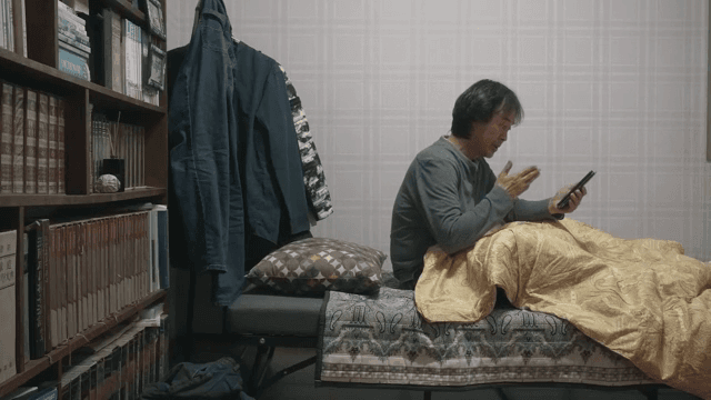 Man sitting on bed talking on smartphone